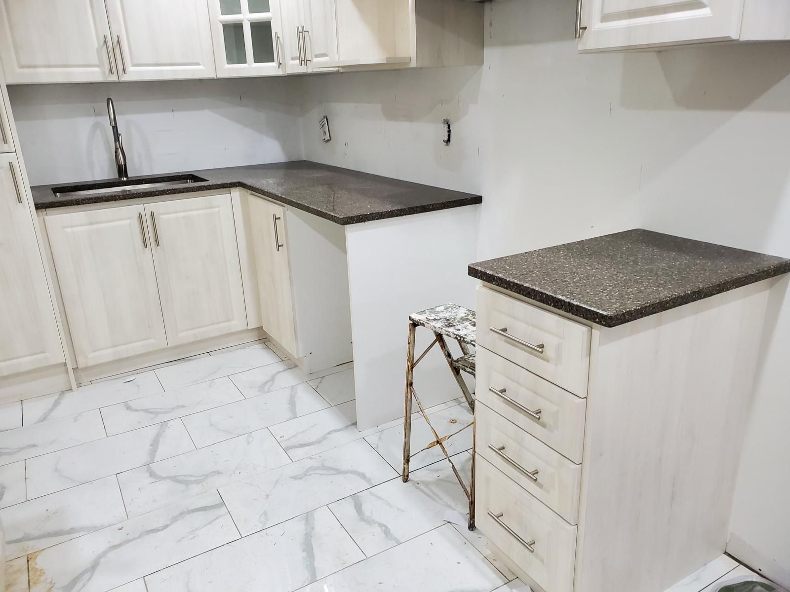 Dark speckled countertops on white kitchen cabinets