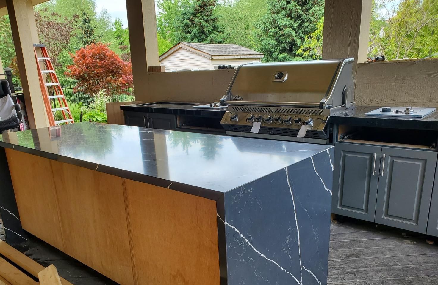 Outdoor kitchen with a black waterfall island and built-in BBQ