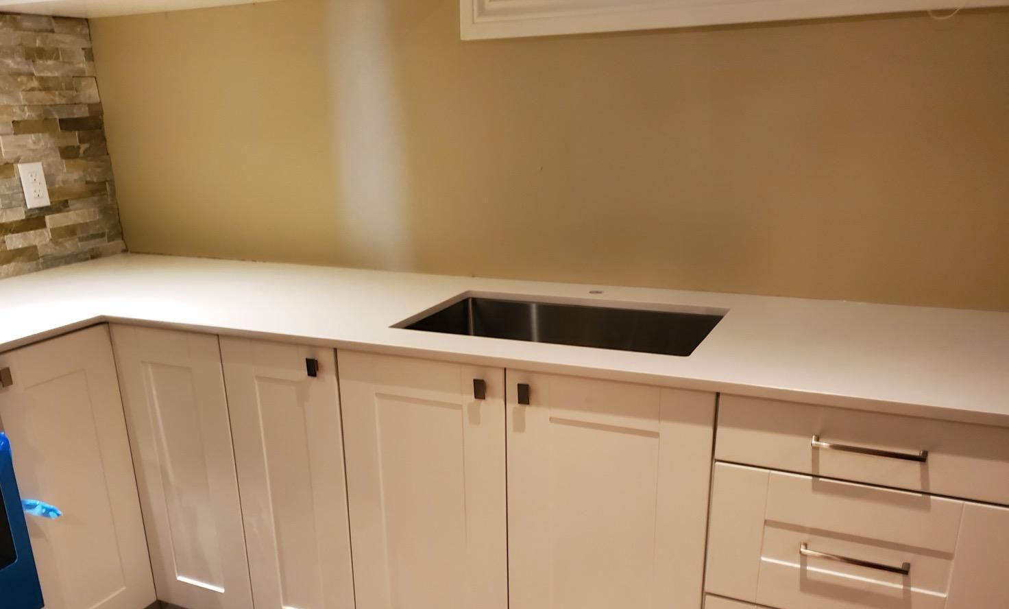 White countertop with an undermount sink on shaker cabinets