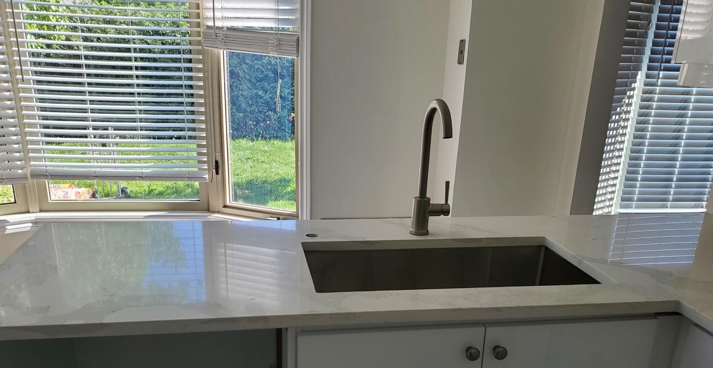 White countertop and undermount sink under a kitchen window