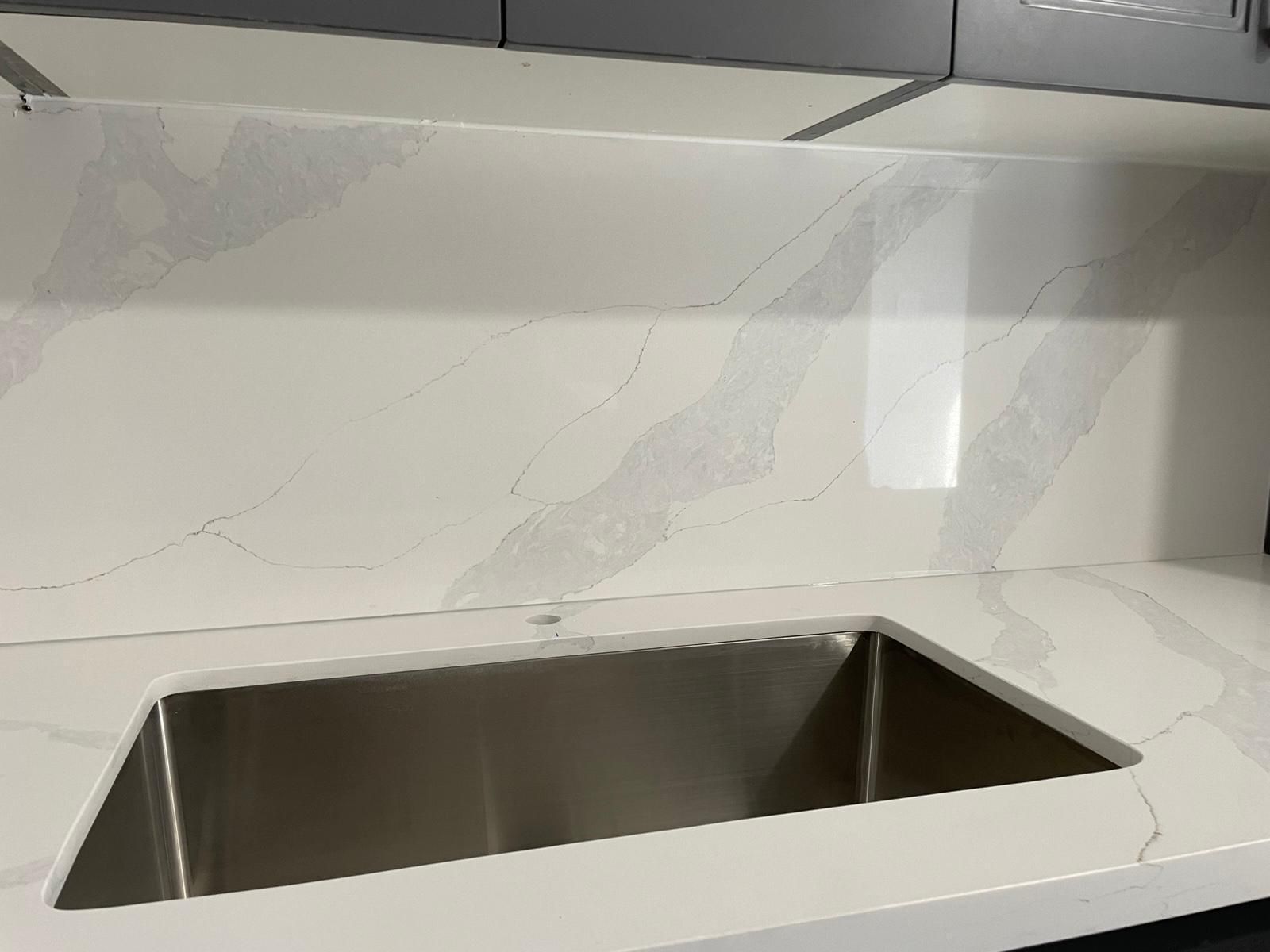 White veined countertop and backsplash with an undermount sink